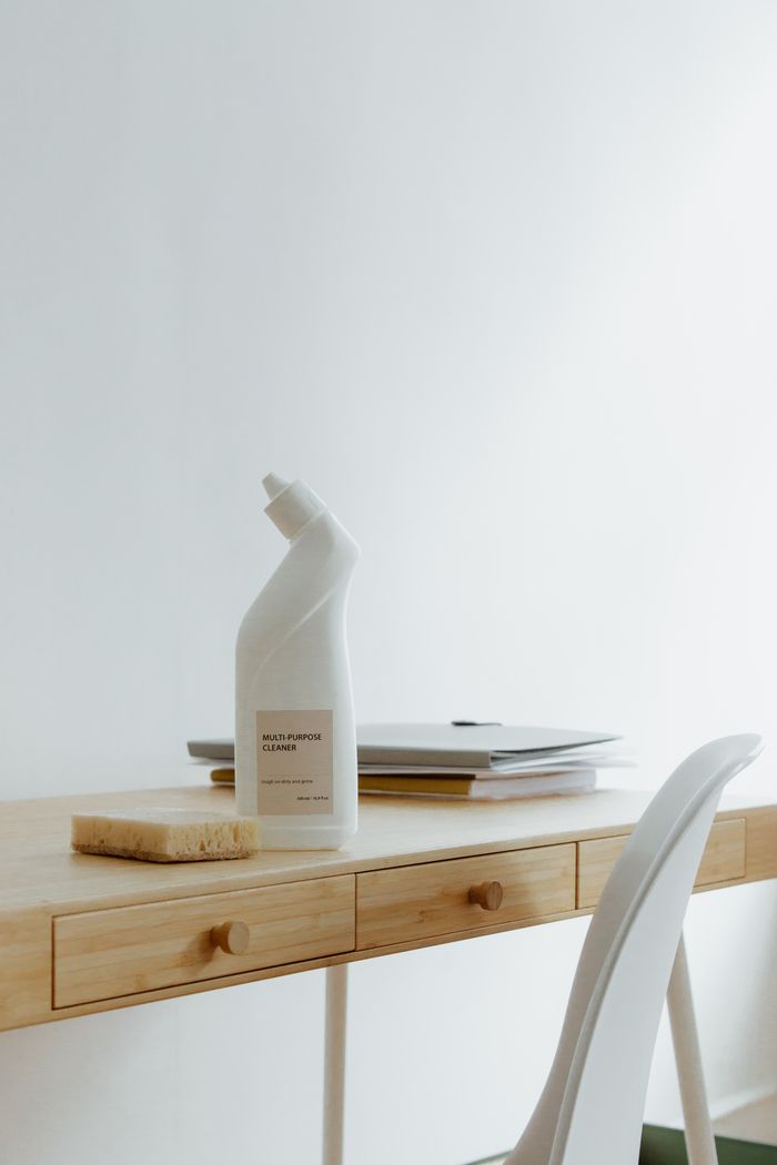 creative-01 A tidy, well-organized home office desk with a cleaning bottle and sponge, highlighting simplicity and practicality.